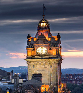 Clock face on tower with evening skyline in background